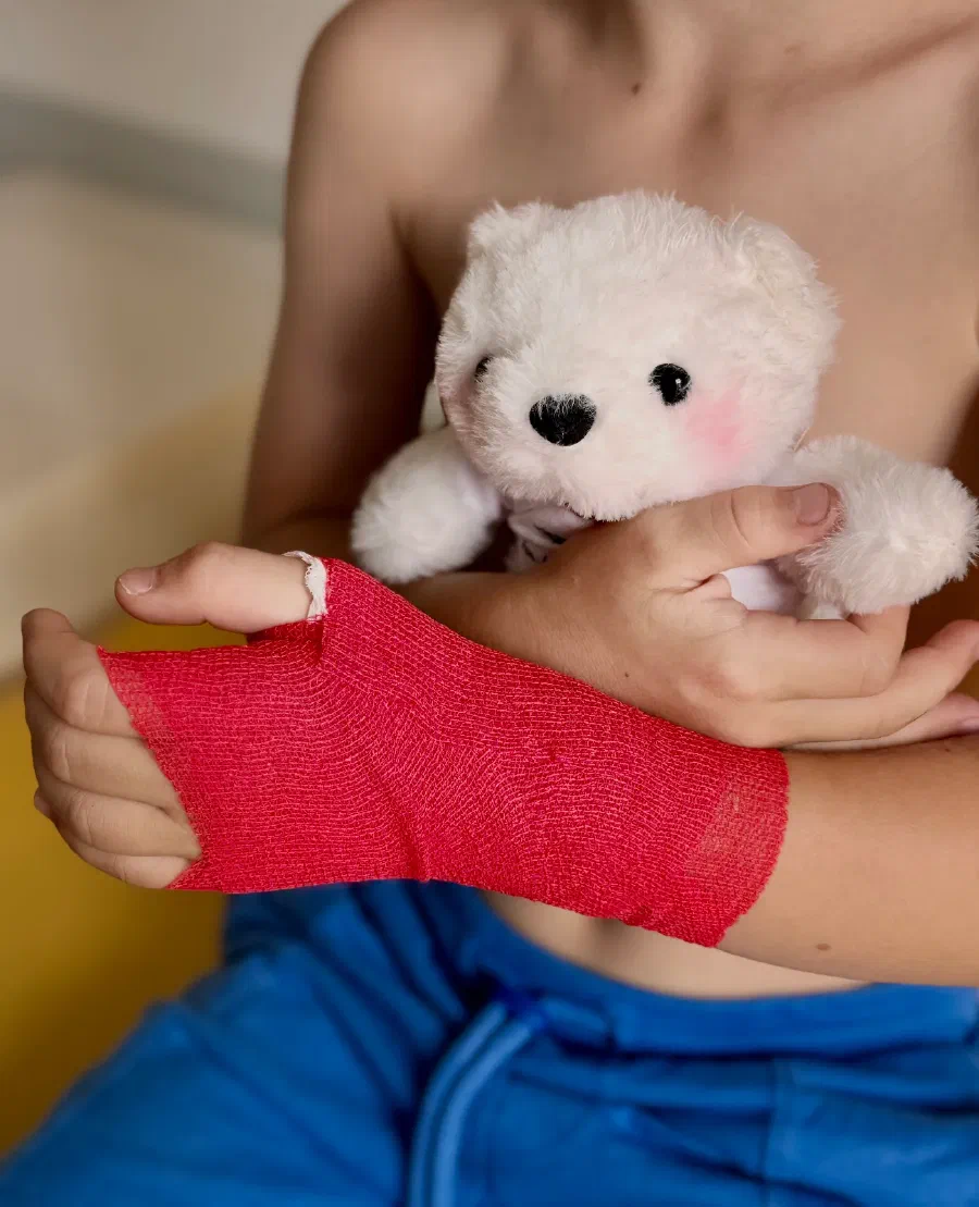 Kind mir Verband am Arm und Teddybär im Arm